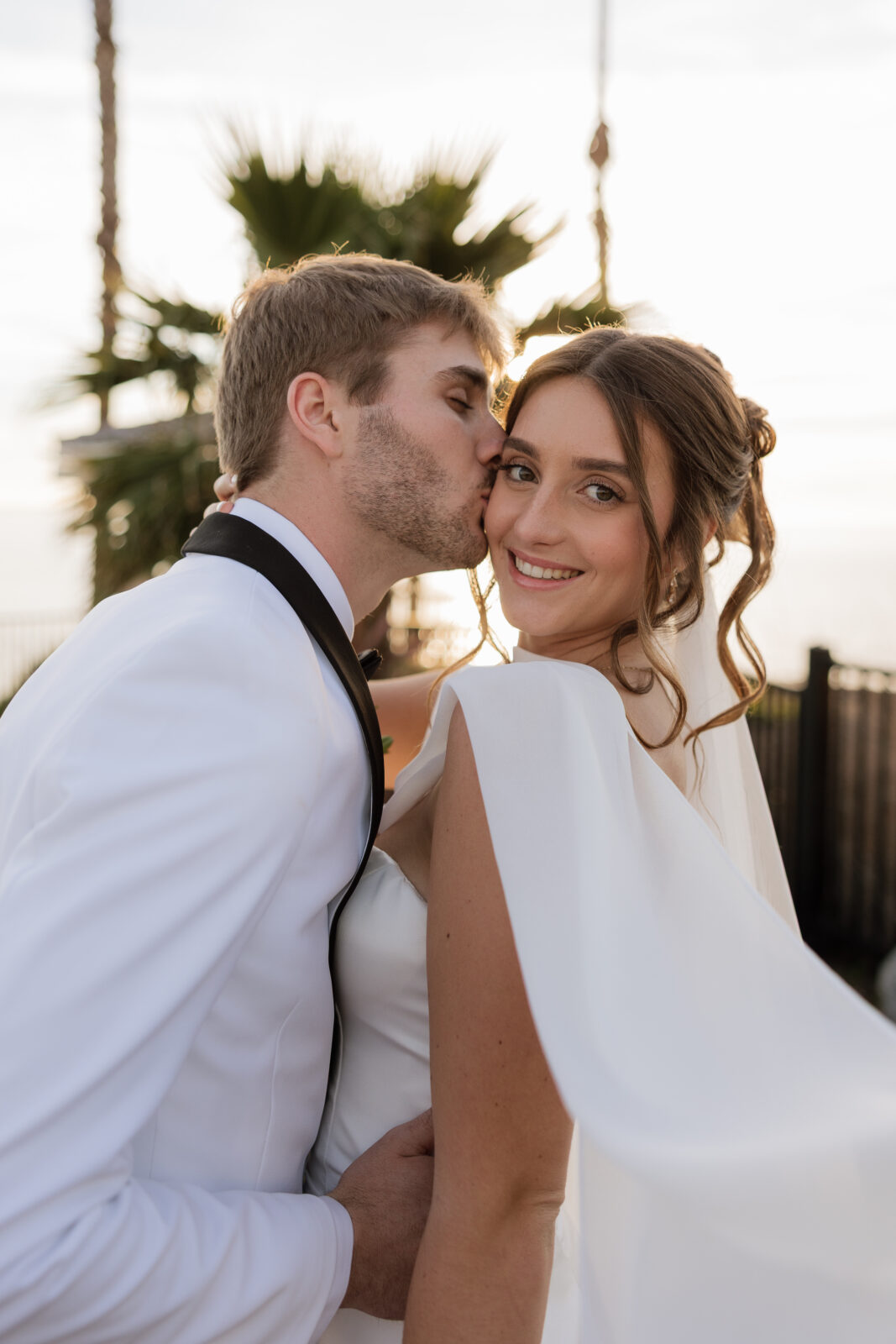 Close-up portrait of bride and groom embracing during golden hour sunset on cliffs in Pismo Beach, California, captured by Southern California wedding photographer