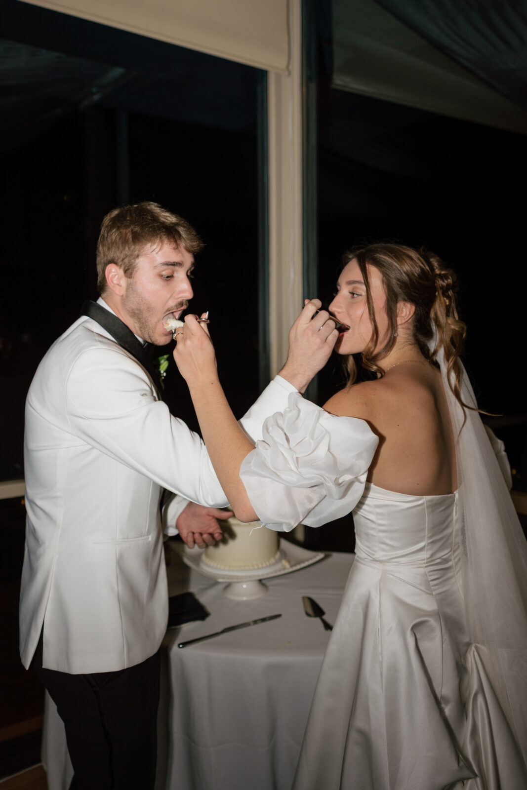 Bride and groom cutting their wedding cake together during reception in Pismo Beach, California, captured by Southern California wedding photographer