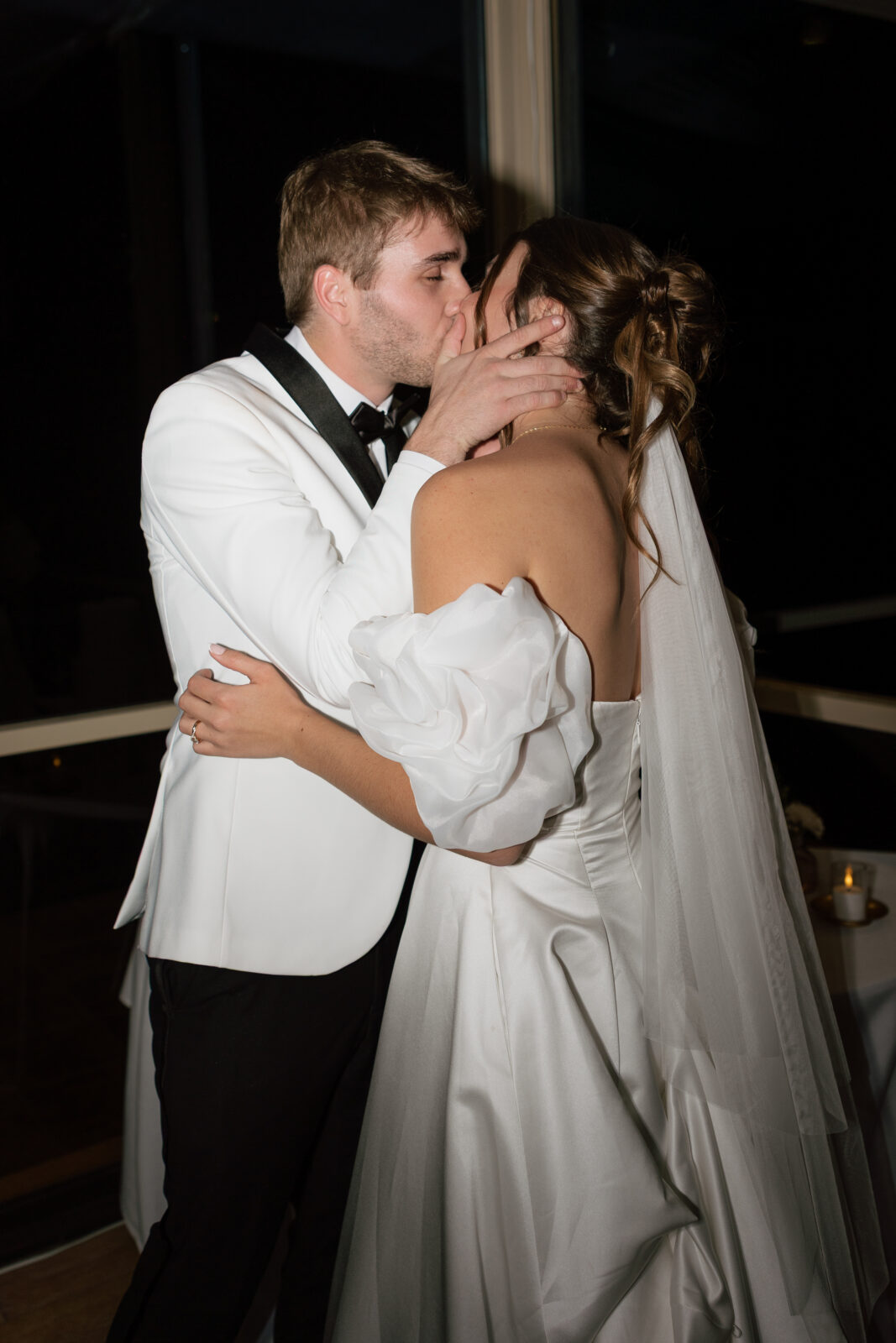 Bride and groom sharing a spontaneous, candid kiss during their wedding reception in Pismo Beach, California, captured by Southern California wedding photographer