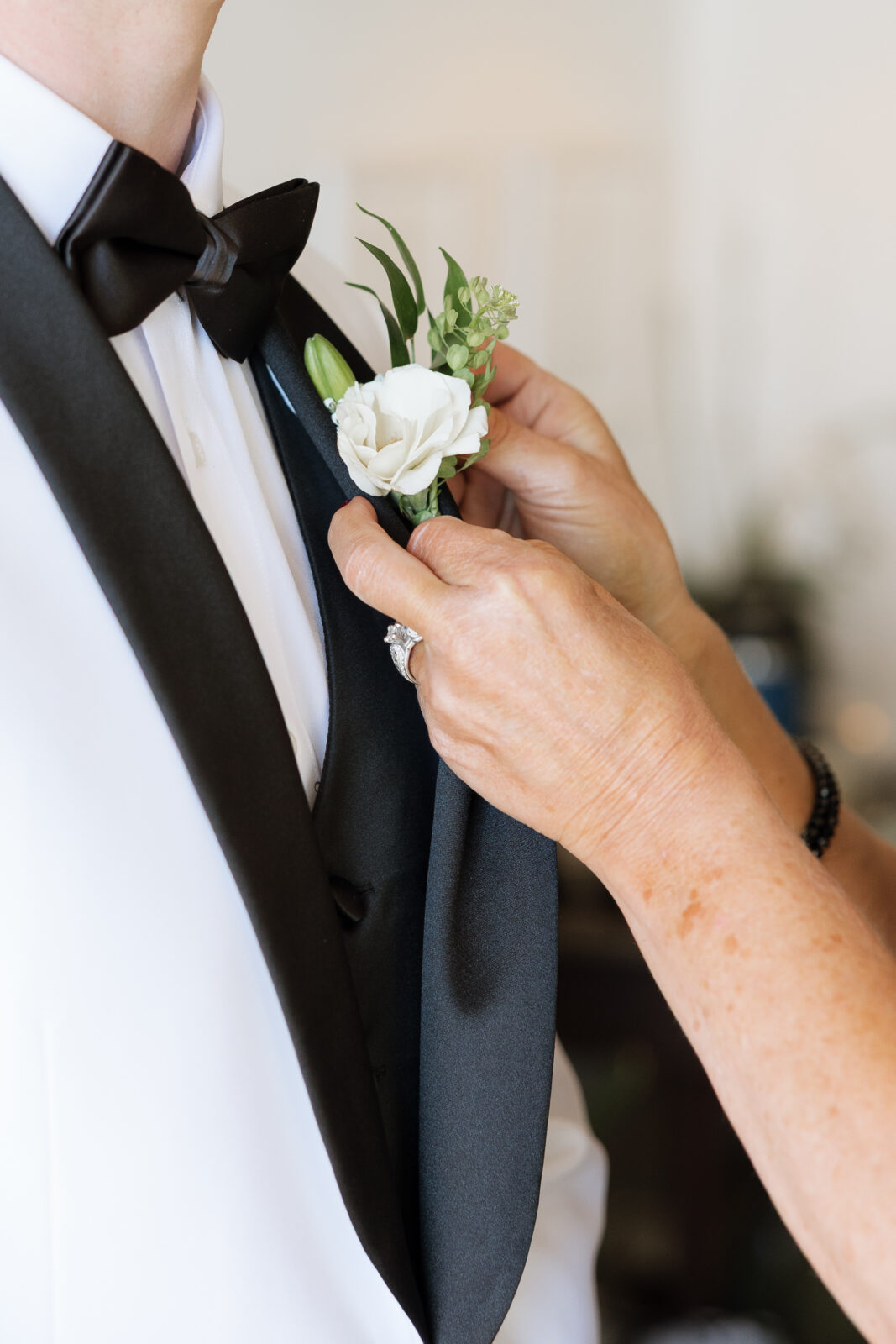 Mother pinning boutonniere on groom during wedding morning in Pismo Beach, California, emotional candid moment captured by Southern California wedding photographer