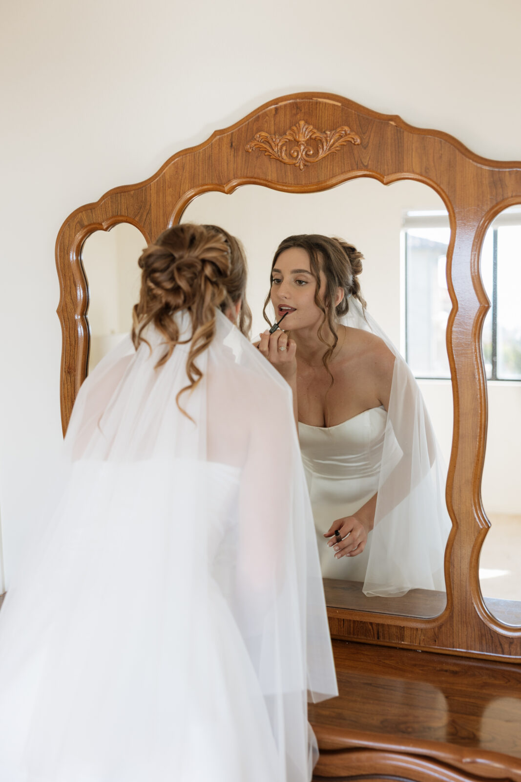 Bride getting ready reflected in mirror, candid wedding morning moment in Pismo Beach, California, captured by Southern California wedding photographer