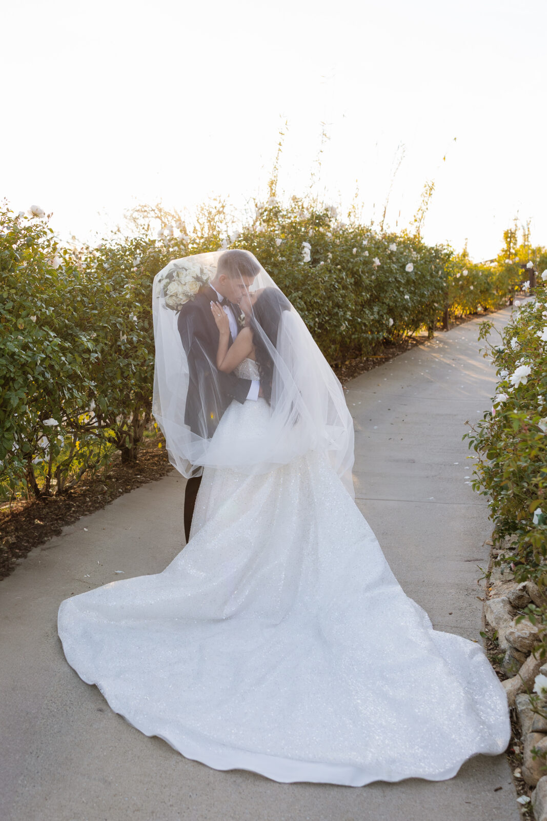 Chelsea and Blake sharing an intimate moment under the bride’s veil at Serendipity Garden wedding venue in Oak Glen, Southern California